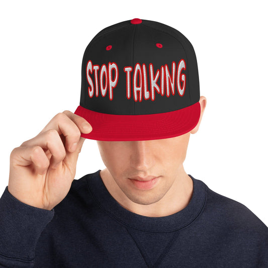 Black and red snapback hat with bold white and red embroidered “Stop Talking” text on the front, flat red brim, and structured crown, shown on a black background...male